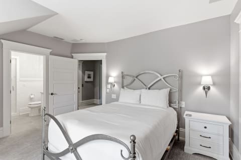 Serene bedroom featuring a metal bed frame, white linens, and a nightstand with soft lighting.