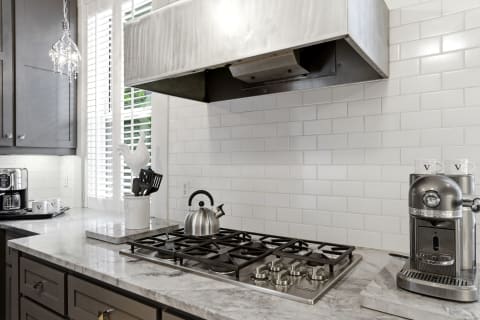 A sleek gourmet kitchen with marble countertops, a stainless steel gas range, and modern appliances.