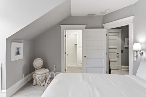 Cozy bedroom featuring gray walls, vaulted ceilings, and a stylish chair.