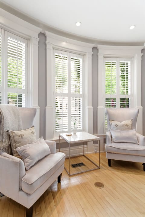 Cozy reading nook with two armchairs and stylish side table by bay windows.