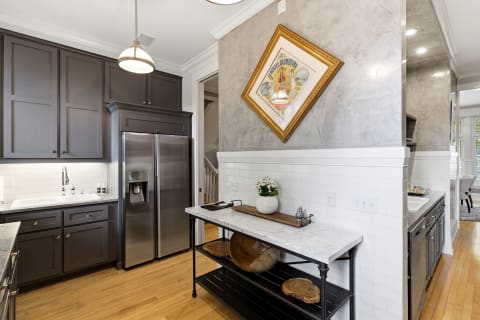 A spacious and modern kitchen with gray cabinetry, stainless appliances, and a decorative island.
