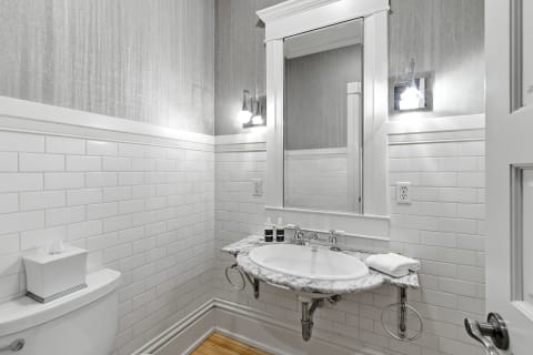 A stylish bathroom with white subway tiles, a marble-topped sink, and modern lighting.