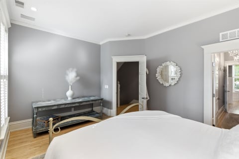 A comfortable bedroom with gray walls, soft white bedding, and a stylish console table.