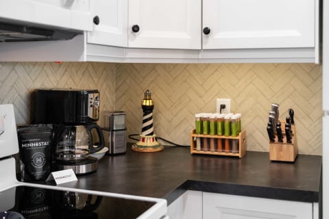 Kitchen counter with a coffee maker, spice tubes, and a lighthouse decoration.