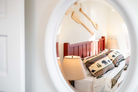 Cozy bedroom with a red headboard, bear-themed bedding, and wooden paddles on the wall.