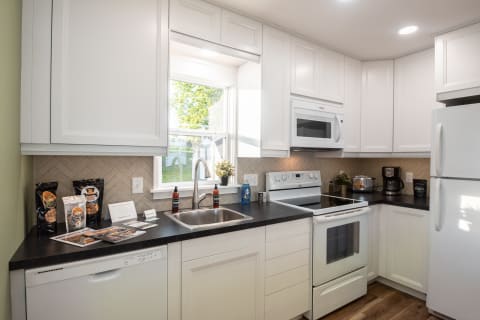 Modern kitchen with white cabinets, dark countertop, and various kitchen appliances.