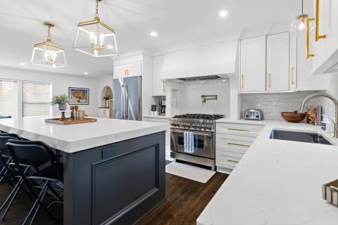 Modern kitchen with marble countertops and stainless steel appliances.