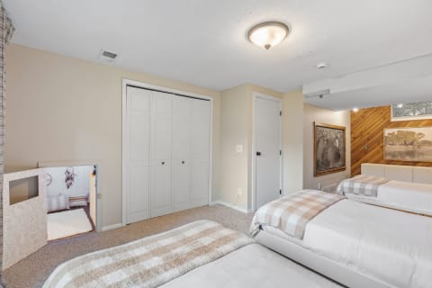 Cozy bedroom with two beds, a closet, a play area, and a chalkboard.