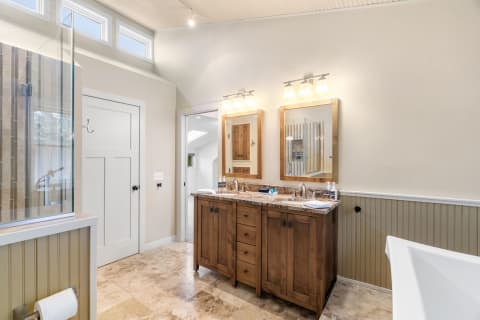 Elegant bathroom with a wooden vanity, mirrors, and a glass shower.