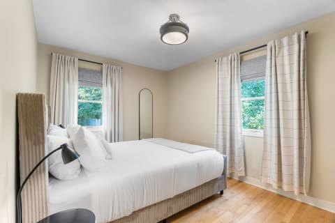 A modern bedroom with a bed, large windows, and contemporary furniture.