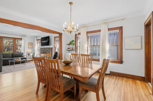 Gather around the warm wood dining table where morning coffee and evening conversations flow beneath the elegant chandelier.