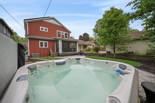 Soak away your cares in your private hot tub, surrounded by a peaceful backyard retreat with lush green lawn and mature trees—pure relaxation awaits.