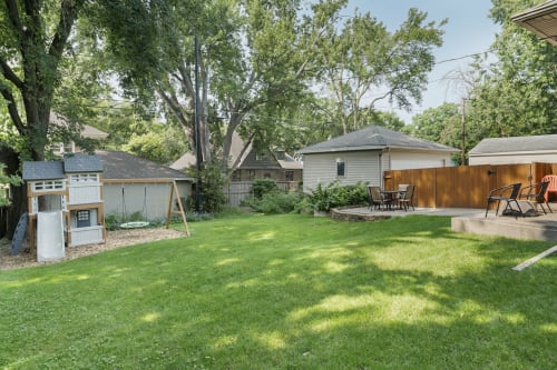Spacious private backyard with lush green lawn, mature shade trees, and comfortable outdoor seating areas for your perfect retreat.