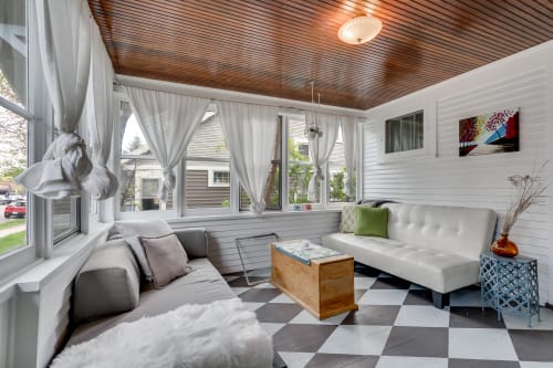 Sink into plush seating where warm wood ceilings and flowing curtains create your perfect retreat for morning coffee or evening relaxation.