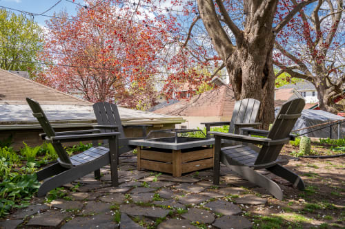Unwind in your private backyard oasis beneath vibrant autumn trees, where cozy Adirondack chairs invite peaceful moments with coffee or evening conversations.