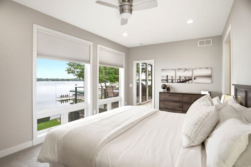 Wake up to stunning lake views from your serene bedroom retreat, where floor-to-ceiling windows frame nature's beauty. Drift off beneath the gentle breeze of the ceiling fan while soaking in waterfront tranquility.