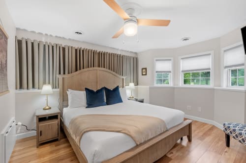 Drift off in your serene bedroom featuring crisp linens, elegant navy accents, and calming natural light from oversized windows.