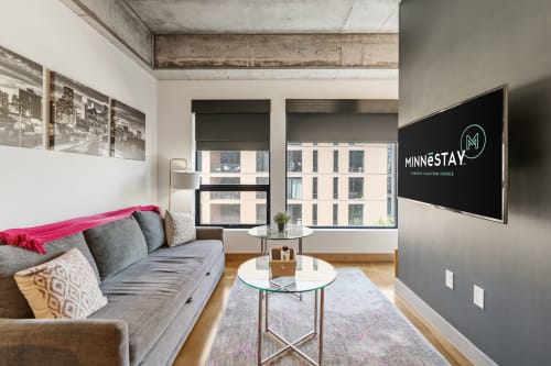 Relax in your stylish living room with exposed concrete ceilings, modern furnishings, and city views through large windows.