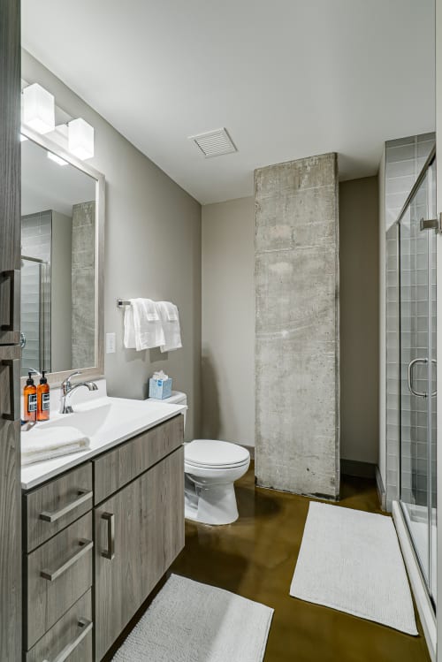 Step into your sleek modern bathroom with industrial concrete accents, spacious glass shower, and thoughtful amenities.
