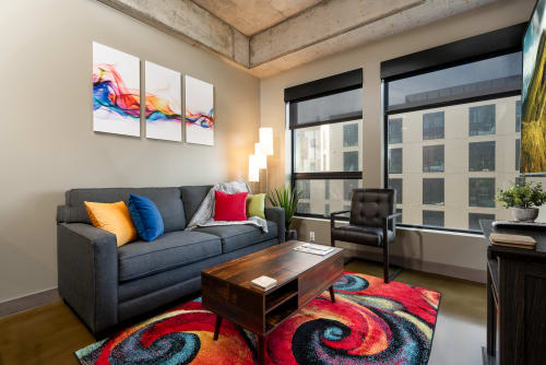 Settle into your stylish living room with a vibrant colorful rug and modern exposed beam ceiling.