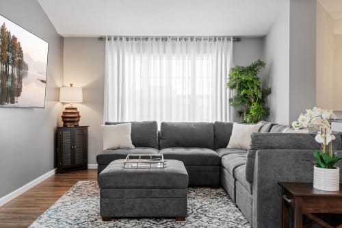 Sink into this plush sectional sofa in your bright living space, where natural light flows through sheer curtains.