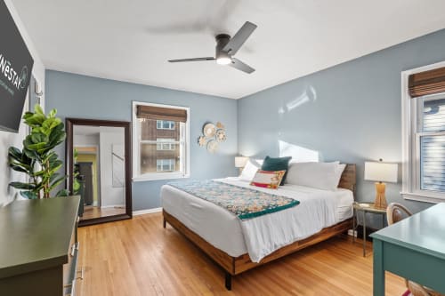 Relax in your serene bedroom with soothing blue walls, crisp linens, and warm wood floors that invite peaceful mornings.