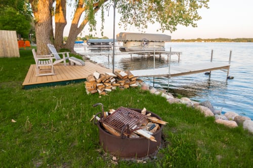 Your private lakefront paradise awaits with a fire pit for evening gatherings, dock access, and peaceful seating under towering trees.